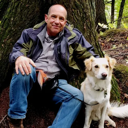 Dr. Dale Covy with white dog in front of a tree